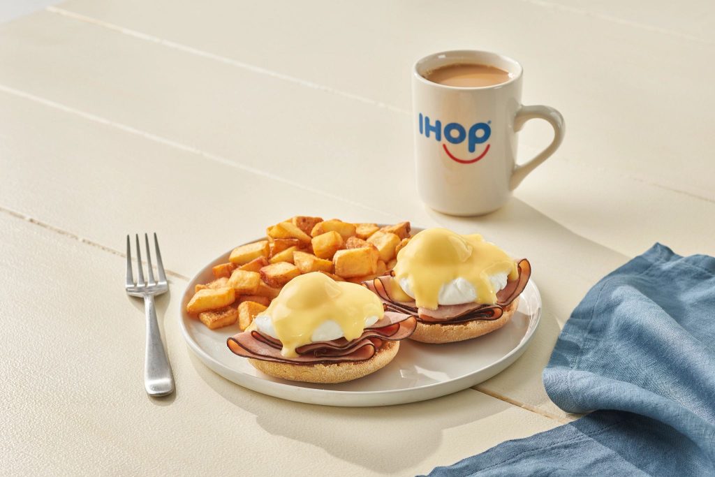 A cup of IHOP signature Colombian blend coffee next to a plate of pancakes.